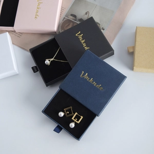 Detail of drawer-style jewelry boxes in various colors with ribbon pulls and gold logo