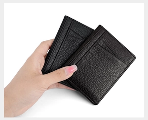 Detail of hand holding two slim black leather card holders with litchi grain texture
