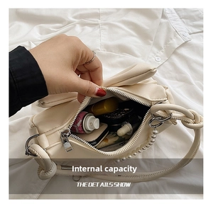 Interior view of cream bow shoulder bag showing storage for lipstick and cosmetics