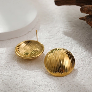 Close-up of gold stainless steel round stud earrings with vertical striped textures