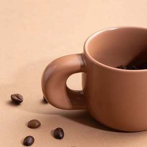 Minimalist matte terracotta ceramic coffee mug with a thick handle on brown background