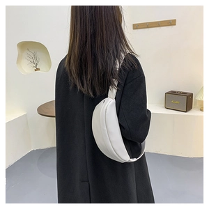 Detail view of a white crescent crossbody bag styled on a black coat for women