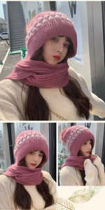 Close-up of pink cable knit winter hooded scarf with a soft white pompom detail