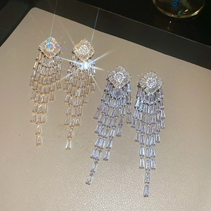 Close-up of gold and silver rhonbus tassel earrings with sparkling zircon gemstones