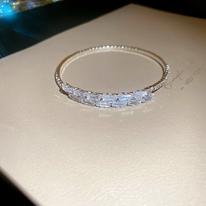 Macro shot of silver baguette-cut zircon stones on a square open bangle bracelet
