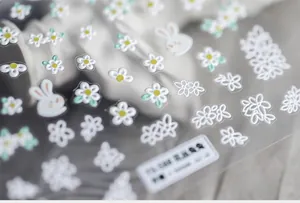 Macro shot of 5D embossed nail stickers featuring white flowers and cute rabbits