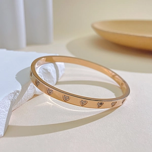 Detail of rose gold stainless steel heart bracelet with shimmering diamond inlay