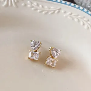 Luxurious gold-plated earrings with heart and rectangular cubic zirconia on a vintage plate