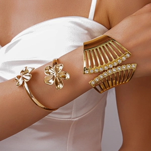 Detail von goldenem Blumenarmreif und breiter Strass-Manschette auf Seide