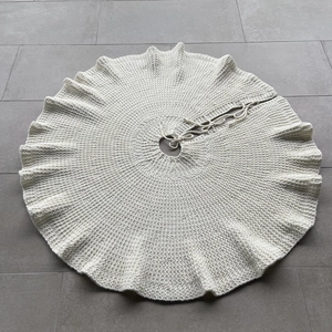 Detail of cream knit Christmas tree skirt showing chunky wool texture and ties