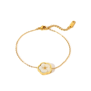 Detail view of a gold stainless steel bracelet with a white shell flower pendant