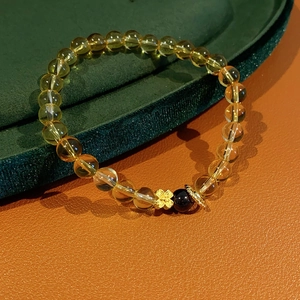 Macro detail of citrine garnet flower bracelet with golden clover charm on velvet