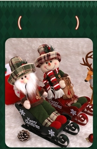 Detail of Santa Claus and Snowman plush figurines on festive metal sleds with pine cones