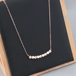 Close-up of rose gold hexagonal necklace featuring clear zircons on black display stand