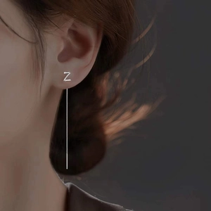 Detail of silver S925 long tassel earrings with Z-shaped charm on female model