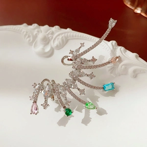 Macro shot of silver wing ear cuff with colorful crystals on a white relief plate