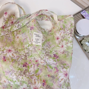 Dettaglio di una borsa tote in tela a fiori con etichetta bianca su una scrivania