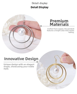 Detailed macro view of brass double hoop earrings with a large white pearl drop pendant