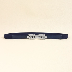 Close-up of a navy blue elastic waist belt featuring a silver leaf-shaped metal buckle
