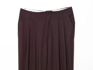 Detail of high-waist dark brown suit trousers featuring elegant double pleats and fine texture