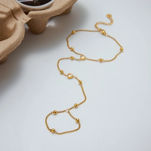 Macro detail of 18K gold double layer bracelet featuring beads and heart charms