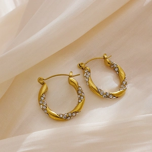 Detailed macro of gold twisted hoop earrings with sparkling rhinestones on silk