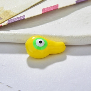 Macro shot of yellow resin gourd-shaped bead with green evil eye detail for DIY jewelry