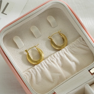 Close-up of gold twist hoop earrings with granular texture in a pink jewelry box