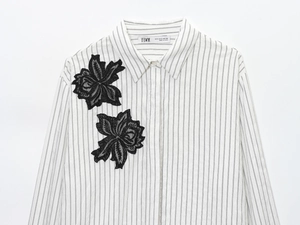 Detail of white striped shirt featuring intricate black hollow lace flower appliques