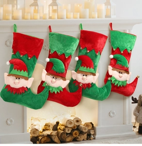 Set of four velvet Christmas elf stockings with bells hanging on a festive fireplace