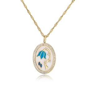 Detail view of a gold oval pendant featuring blue floral enamel and crystal inlay