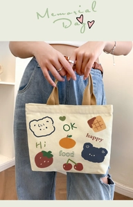 Detail view of beige canvas tote bag with cute bear illustrations and khaki handles