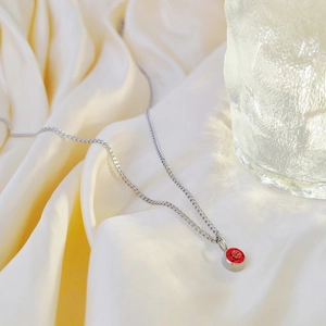 Zilveren ketting met rode geboortesteen hanger op elegant crèmekleurig zijde