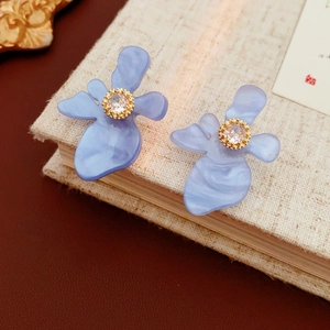 Détail de boucles d'oreilles en résine bleue avec zircon doré sur un fond de livre ancien