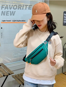 Detail of green nylon crossbody bag with dual zipper compartments and earphone port