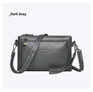 Detail of dark gray multi-layer crossbody bag featuring metal accents and zip pockets