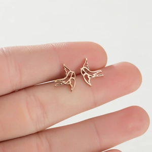 Macro shot of rose gold swallow earrings with hollow design held in hand