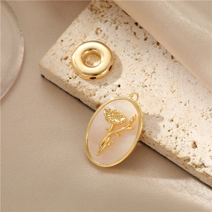 Gold flower shell pendant and bead displayed on a textured stone over silk fabric