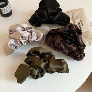 Detail of four silk pleated satin hair claws in black, gold, brown and dark green