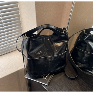 Close-up of black bucket bag with pleated texture and glossy finish in a modern room