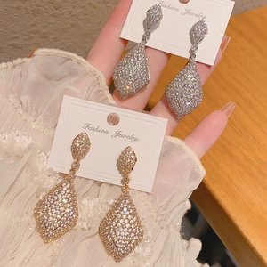 Détail de boucles d'oreilles pendantes géométriques serties de zircons brillants pavés