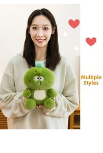 Close-up of cute green plush monster toy with soft fabric held by a model in a home setting