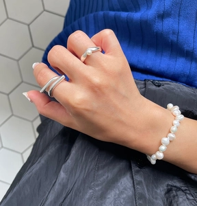 Detail of 925 sterling silver geometric rings and pearl bracelet worn on hand