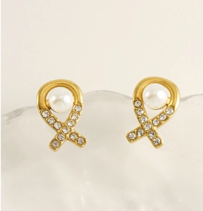 Détail de boucles d'oreilles ruban doré avec strass et perle d'imitation blanche