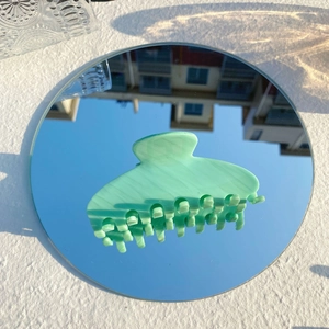 Détail de la pince à cheveux en acétate vert menthe montrant la texture marbrée sur miroir