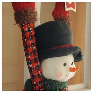 Detailed view of cute plush snowman ornament with green scarf and red plaid long arms