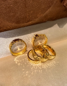 Detailed view of 18k gold plated wide band rings with textured hammered surface on silk