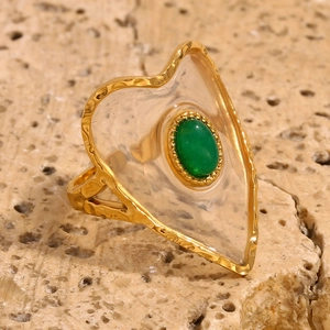 Detail of 18K gold heart ring with green stone inlay and hammered metal texture
