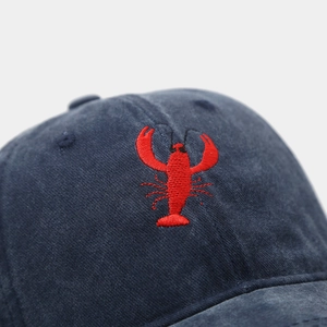 Macro shot of red lobster embroidery on navy blue washed cotton baseball cap texture
