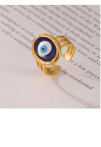 Detailed macro of gold multi-layer ring with blue evil eye motif on vintage book background